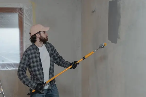 Painter rolling grey paint onto an interior wall in Boise